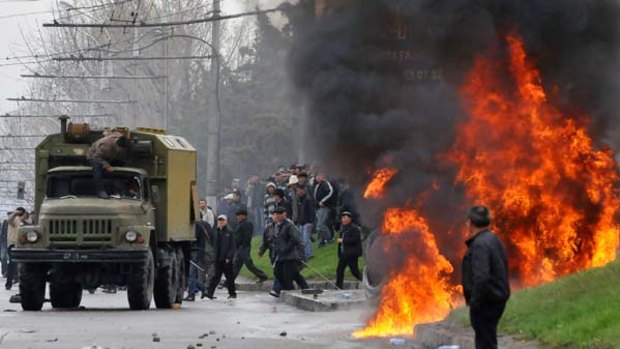 Kyrgyz opposition supporters attack a Kyrgyz riot police vehicle during an anti-government protest in Bishkek.