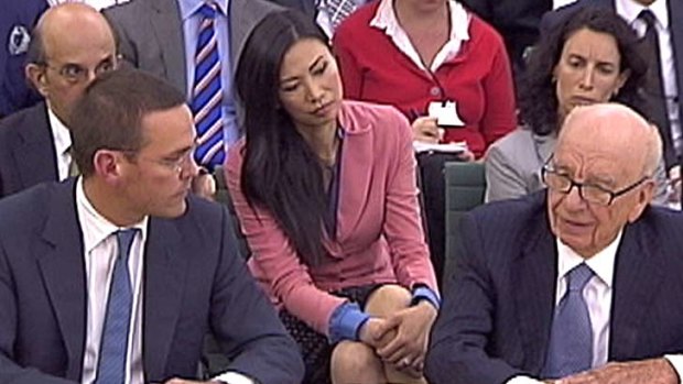 James (left) and Rupert Murdoch (right) answer questions from British politicians, with Rupert's wife Wendi (centre) watching on.