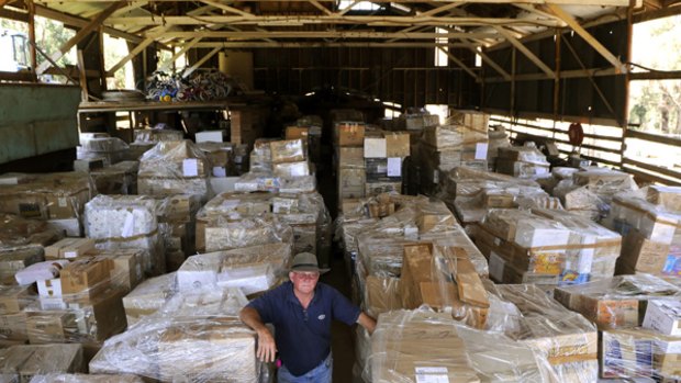 Volunteer John Gough, of Sydney, and the 90 pallets of goods waiting for distribution from a disused dairy shed near Marysville.