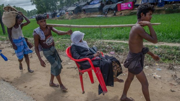 A sick Rohingya Muslim woman, Amila Khatoon, is carried on a plastic chair, by her sons on the way to hospital outside the refugee camp in Bangladesh.