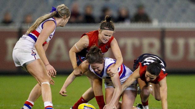 Emma Kearney (centre) of the Western Bulldogs competes for the ball against Melbourne in the inaugural AFL women's match at the MCG.