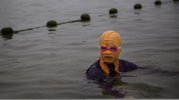 Looking orange ... A Chinese woman wears a facekini while swimming in the Yellow Sea in Qingdao, China.