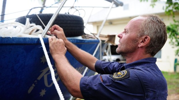 A volunteer Coastguard member helps tie down a boat in Port Douglas before Tropical Cyclone Ita made landfall.