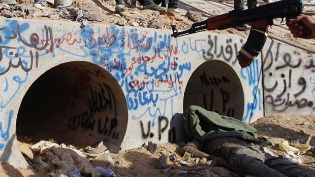 Last stand ... an anti-Gaddafi fighter points at the drain where Muammar Gaddafi was reportedly hiding before he was captured.