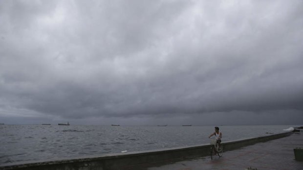 A man rides his bicycle as storm clouds gather over Navotas, north of Manila, on Monday.