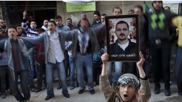 Violence ... a boy holds up a portrait of a man killed by the Syrian army.
