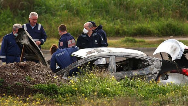 Fire death: Police, forensics personnel and Metropolitan Fire Brigade officers probe the car wreckage and the surrounding area in Keilor East yesterday.