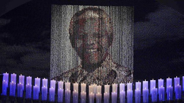 Candles are lit under a portrait of Nelson Mandela before his funeral ceremony.