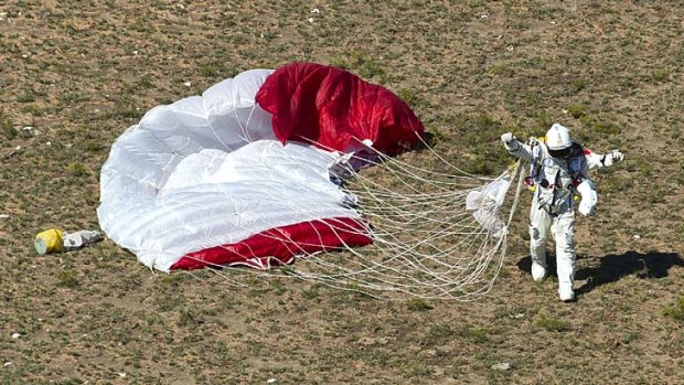 Job done ... Felix Baumgartner celebrates afterlanding in the desert.