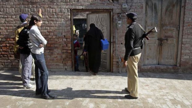 A policemen stands guard as workers wait to give polio drops to children in Lahore.
