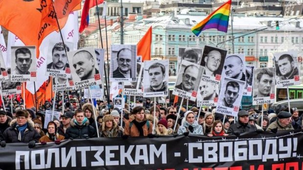 People carry pictures of political prisoners and a banner reading 'Freedom for political prisoners!' during an opposition rally in  Moscow.