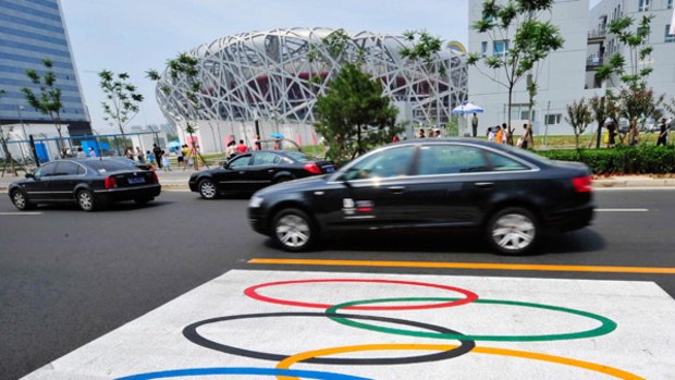Drivers pass the Olympic lane in Beijing, where traffic restrictions will take half the city's 3.3 million cars off the road for three months. 