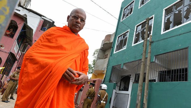 Simmering tensions: A Sri Lankan Buddhist monk walks past the vandalised mosque.