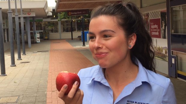 Emily Kelly crunches into a waxless apple outside the Coles store in Curtin. 