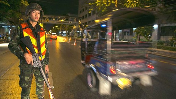 A Thai soldier stands guard at a checkpoint after a curfew started at 10pm in Bangkok, Thailand.
