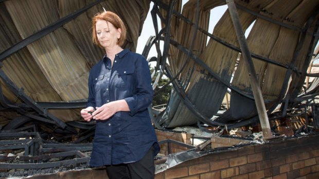 Prime Minister Julia Gillard inspects ashes she picked up from the ruins of The Dunalley Primary which was destroyed by the bushfire that swept through the Tasmanian community on Friday night.