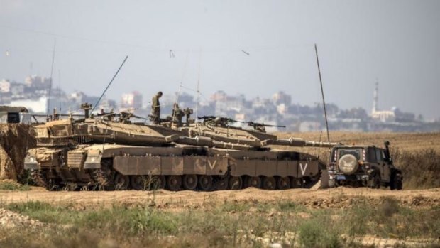 Troops deployed ... Israeli soldiers sit atop their tanks on the Israeli side of the border with the Gaza Strip.