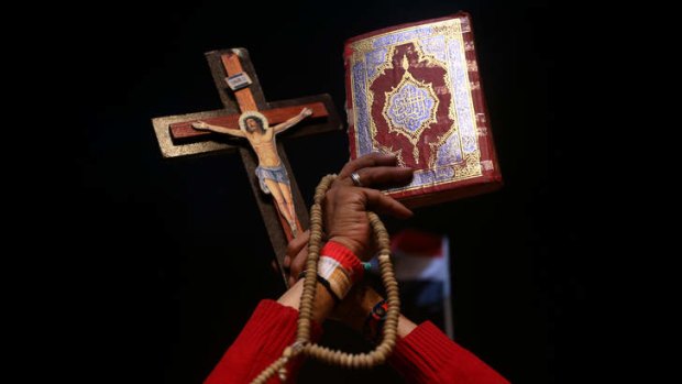 An opponent of ousted President Mohammed Mursi holds up Islam's holy book Koran, right, and Christian cross to show unity during a rally at Tahrir square, in Cairo,   on Friday.