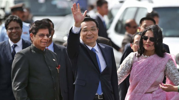 Chinese Premiere Li Keqiang waves as he is received by Indian Junior Minister for External Affairs, E. Ahamed, after he arrives in New Delhi, India, Sunday, May 19, 2013. A woman at right is a protocol officer.