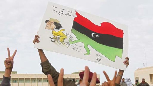 Protesters chant anti-government slogans while holding a banner depicting Libyan leader Muammar Gaddafi in Tobruk.