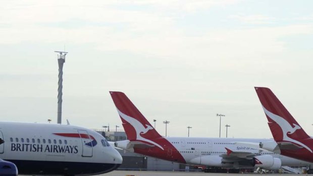 A British Airways jet passes grounded Qantas aircraft parked at Heathrow Airport.