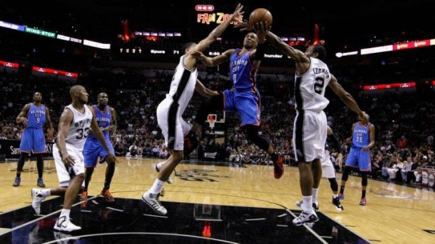 Russell Westbrook of the Oklahoma City Thunder drives to the basket against Tim Duncan and Kawhi Leonard of the San Antonio Spurs.