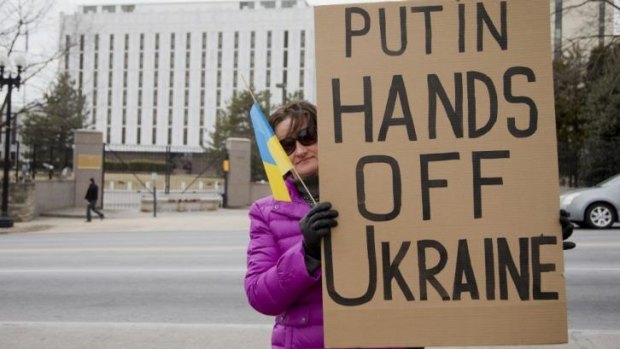 Taisia Bullard, who was born in central Ukraine, holds a protest banner in front in the Russian embassy in Washington. 
