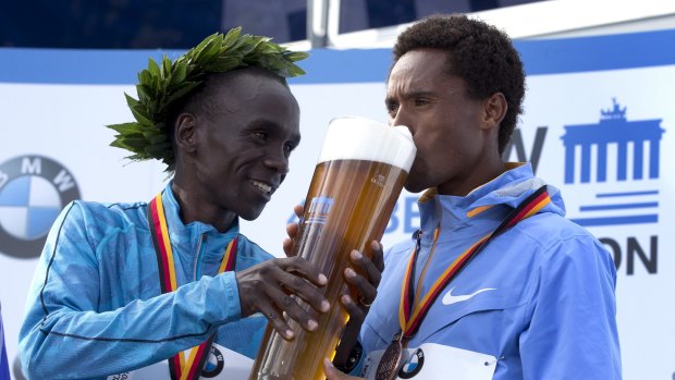 Bottoms up: Eliud Kipchoge feeds a beer to third placed Feyisa Lilesa. 
