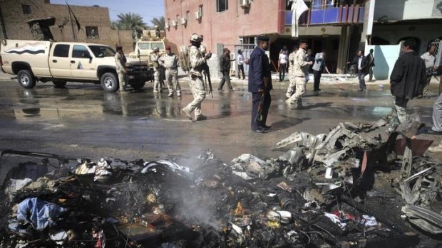 Iraqi security forces inspect the site of a bomb attack in Kerbala.