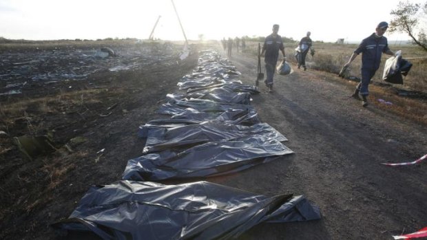 Body bags rest largely unguarded by the side of a road near the crash site.