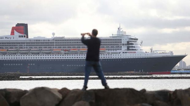 A passer-by takes a photo of Queen Mary 2 at Webb Dock.
