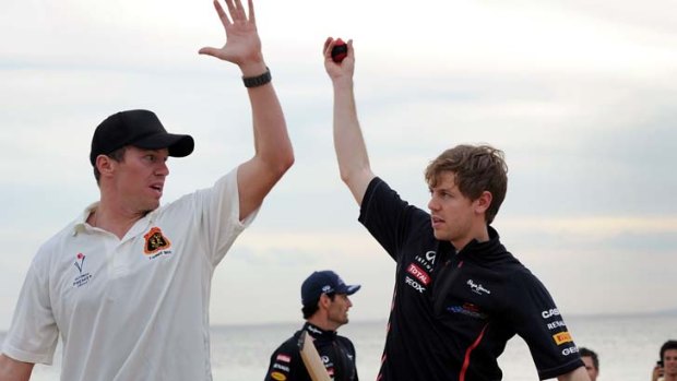 Like this: Peter Siddle (left) shows Sebastian Vettel how to bowl a cricket ball at St Kilda Beach yesterday.