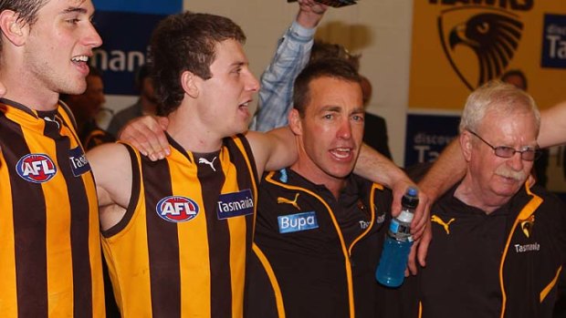 Alastair Clarkson (2nd right) sings the team song with the players in the dressing room after his team defeated Collingwood.
