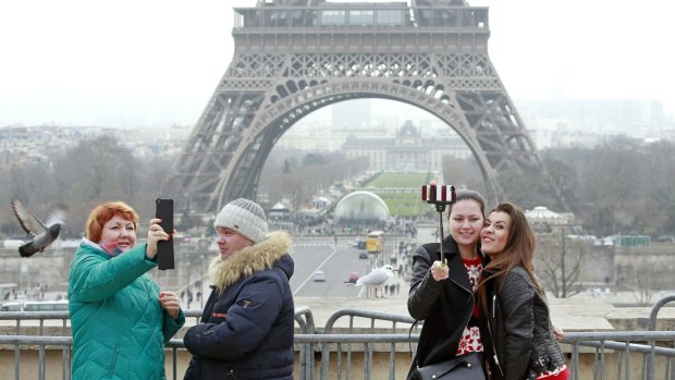 Tourists use a selfie stick on the Trocadero Square, with  the Eiffel Tower in background, in Paris.