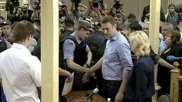 A police officer puts on handcuffs on Russian opposition leader Alexei Navalny after a trial in Kirov, Russia, Thursday, July 18, 2013.