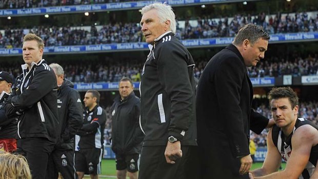 Collingwood coach Mick Malthouse, assistant coach Nathan Buckley, left and president Eddie McGuire right, watch the presentation of the premiership cup to Geelong after Malthouse's final game as Magpie coach, September 2011.