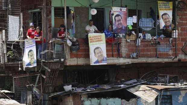 Devotion ... supporters of Hugo Chavez hang portraits of him from their homes as his coffin was driven through the streets of Caracas on Wednesday.