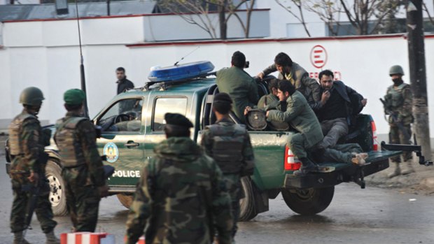 Policemen rush a casualty (partly obscured) on a pickup truck to a hospital following an attack by gunmen at Bekhtar guesthouse in Kabul, where UN staff were killed.