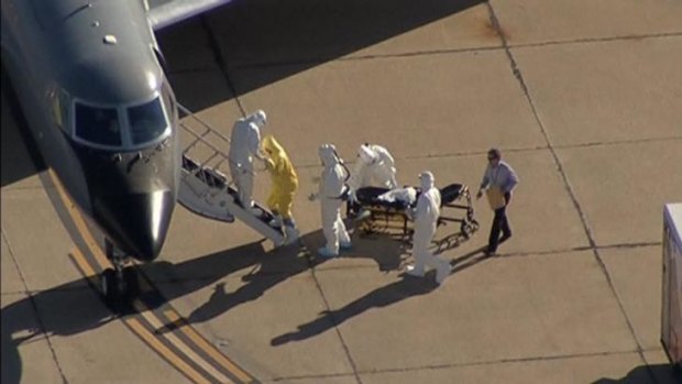 Texas nurse Amber Vinson is helped up the steps of a waiting aircraft by personnel in Hazmat suits - and a man follows behind carrying a clipboard.