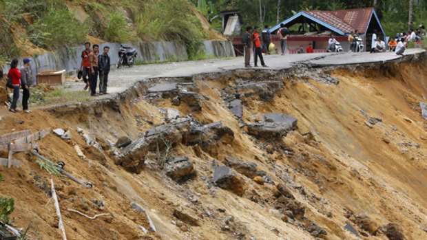 Residents walk along a road, affected by a landslide after the earthquake that devastated West Sumatra.