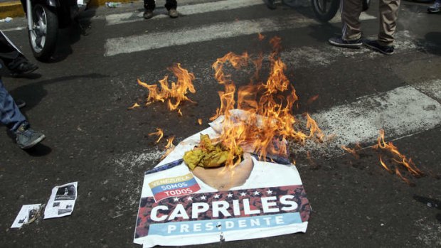 Government "Chavista" supporters burn an election poster of opposition presidential candidate Henrique Capriles in Caracas