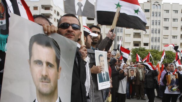 Pro-Syrian regime protesters, hold portraits of Syrian President Bashar Assad and chant against the Arab League, as they gather outside the Syrian foreign ministry.