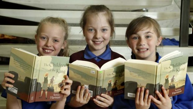 Saint John the Apostle Primary School year 4 students Indie McDonald, Monika Swiderski and Mia Medway reading author Sonya Hartnett's book The Children of the King.