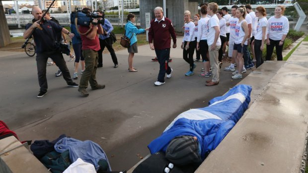 Kevin Rudd and his entourage walk past a homeless man in Brisbane on Tuesday.