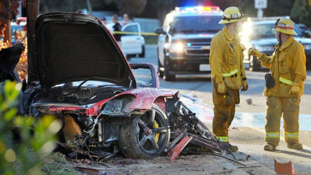Firefighters next to the wreckage of the Porsche that crashed  killing Paul Walker and Roger Roda in November 2013.