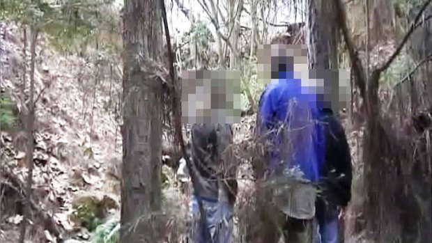 Three police officers at the base of an embankment over which Brett Peter Cowan claimed to have thrown Daniel Morcombe's body.
