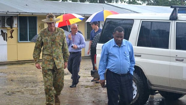 General Campbell, left, and Manus Island Police Chief  Alex N'Drasah, right, with immigration officials as they walk through the area where asylum seekers have been housed with criminals on Manus Island.