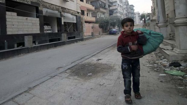 Targets: A boy walks along a damaged street in the Duma neighbourhood of Damascus.