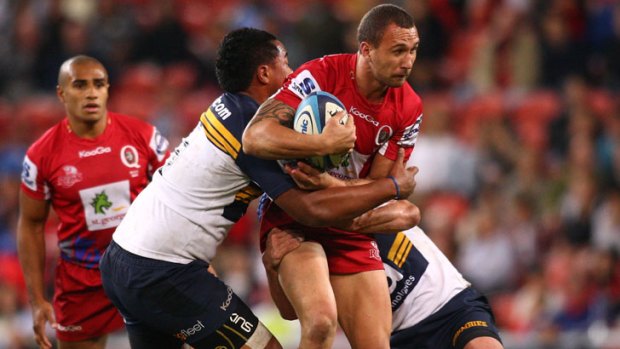 Quade Cooper of the Reds is tackled by the Brumbies' defence.