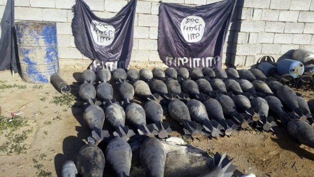 Weapons and explosives confiscated by Iraqi security forces from Islamic State militants on display at an Iraqi army base, with IS flags deliberately hung upside down as a mark of disrespect.